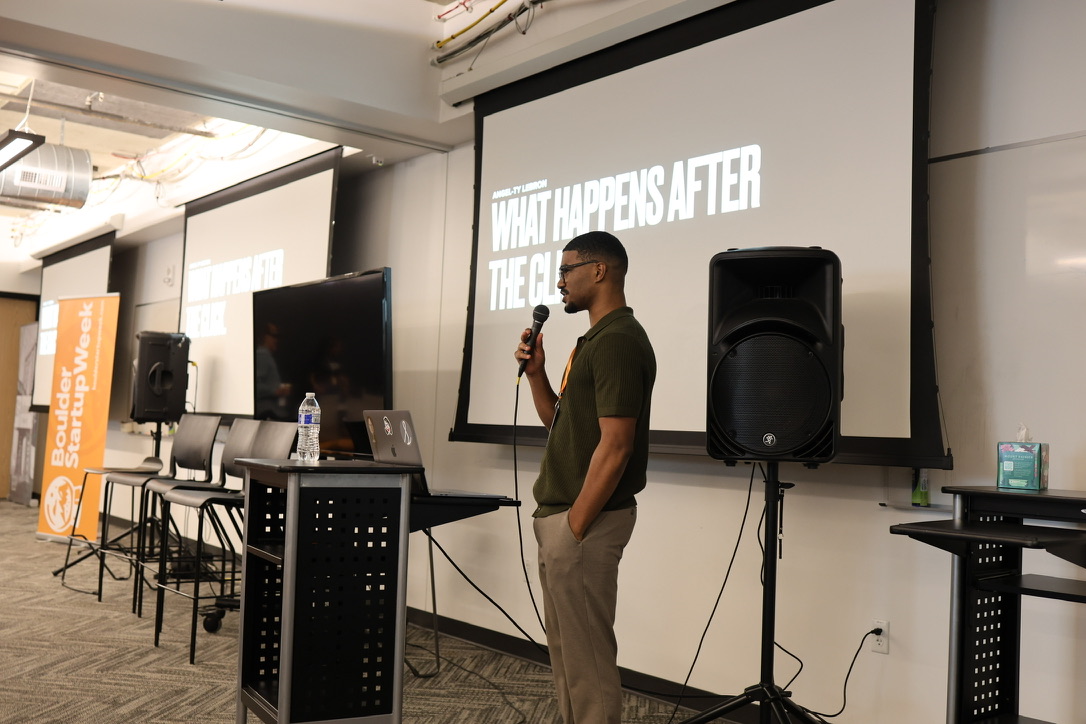 Angel Ty Lebron speaking into a handheld microphone at Boulder Startup Week.